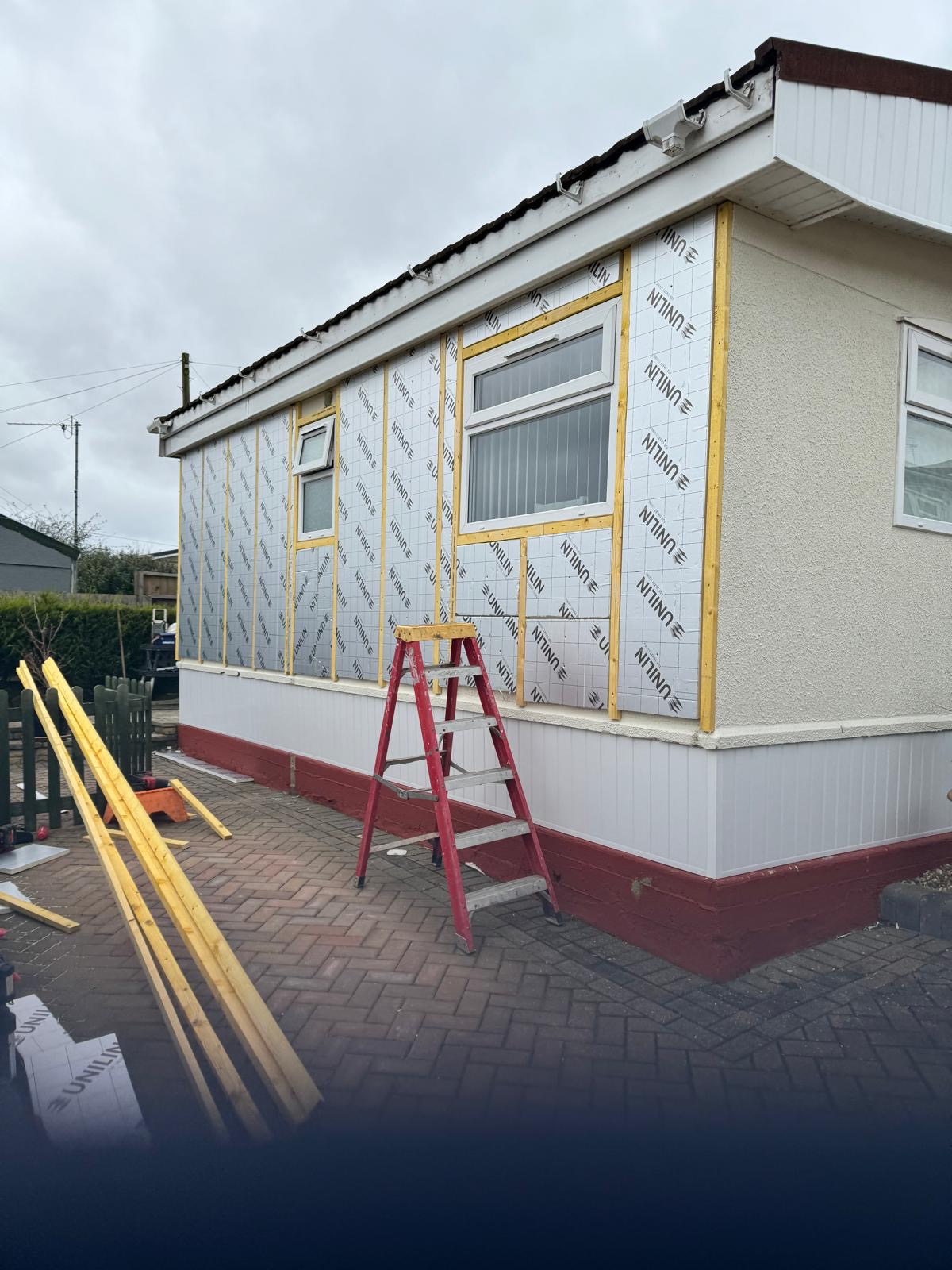 Park home mid-renovation — insulation boards being fitted before new cladding